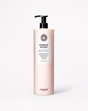 En flaska Maria Nila Mirror Gloss-schampo i en ljusrosa flaska med svart pump och en vit etikett, placerad mitt på en ljusgrå bakgrund.