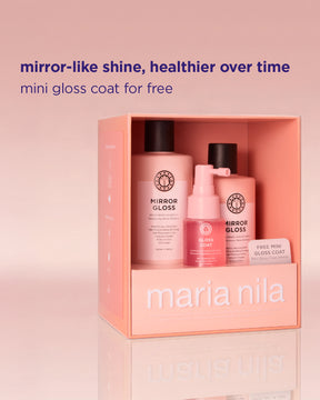 Maria Nila mini Gloss Coat-presentset i en rosa box, med en spegelblank glansflaska, en Gloss Coat-pumpflaska och ett gratis mini Gloss Coat-kort, med reklamtext ovanför på en rosa gradientbakgrund.