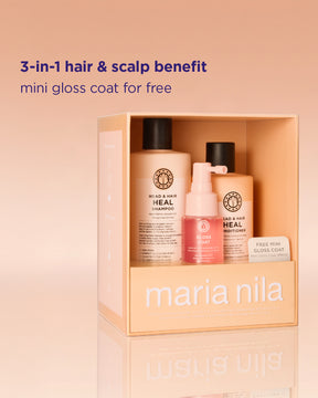 Maria Nila 3-i-1 hår- och hårbottenset i en persikofärgad box, med en schampoflaska, en balsamflaska och en rosa mini Gloss Coat-flaska, med reklamtext på en persikofärgad bakgrund.